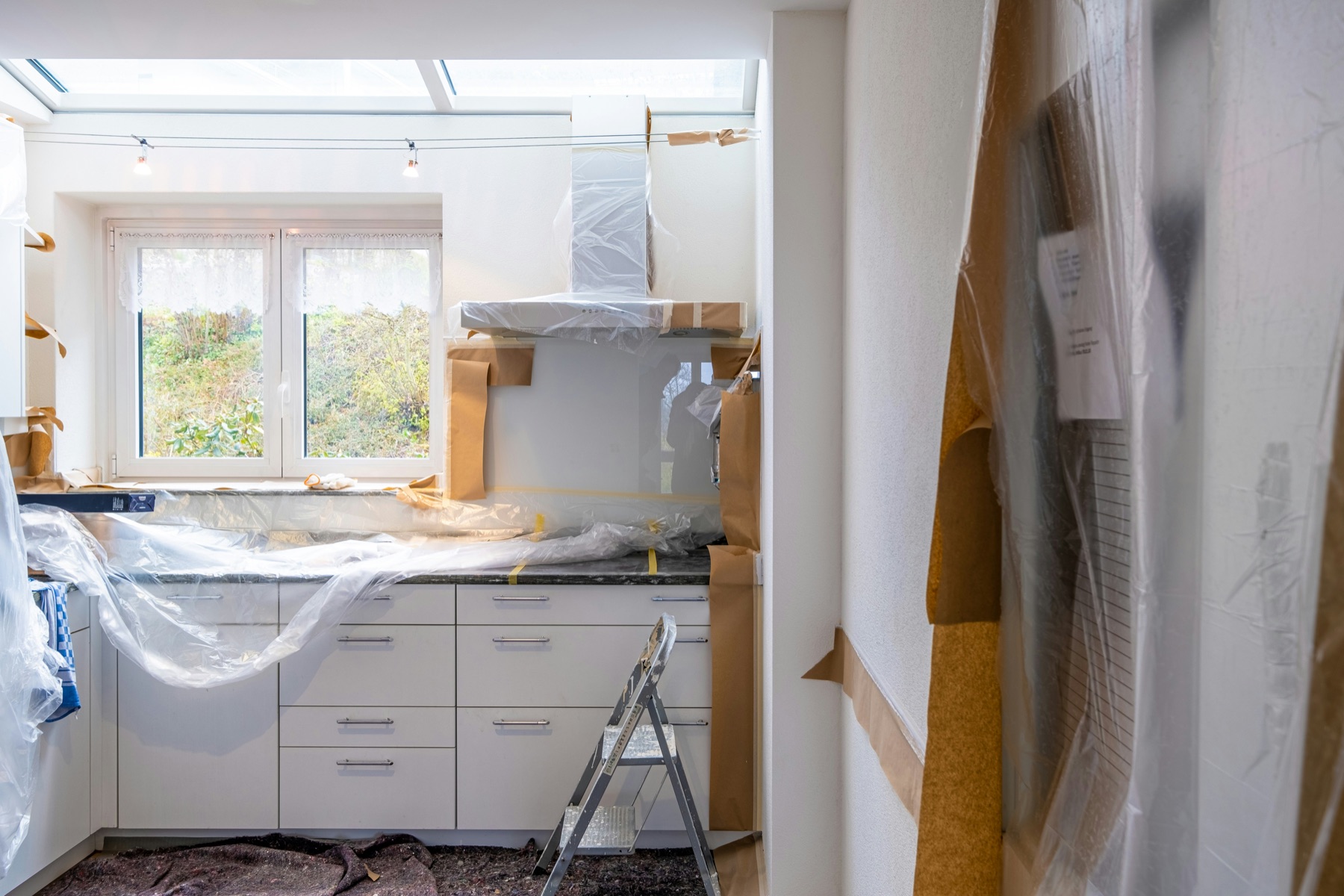 Kitchen remodel in progress, with cabinets and surfaces protected during the renovation