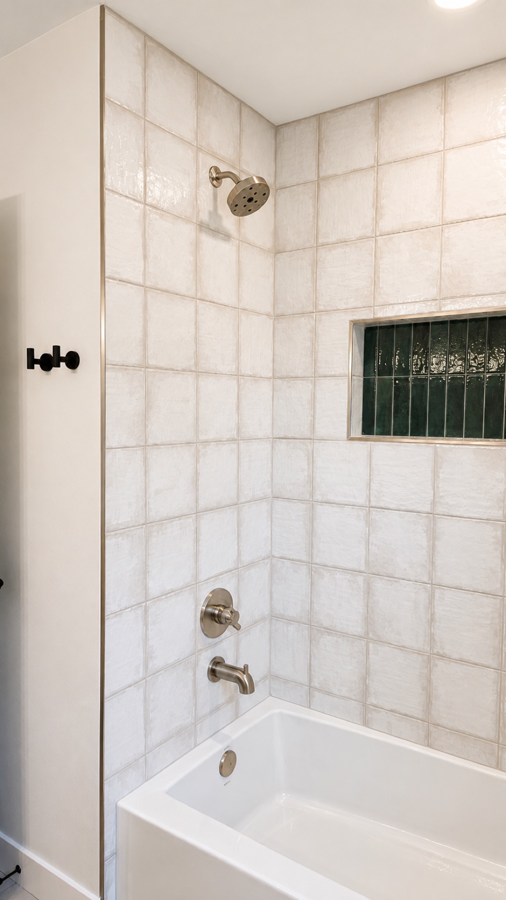 New tub and shower in the hall bathroom with handmade-look white tile and a deep green tile niche