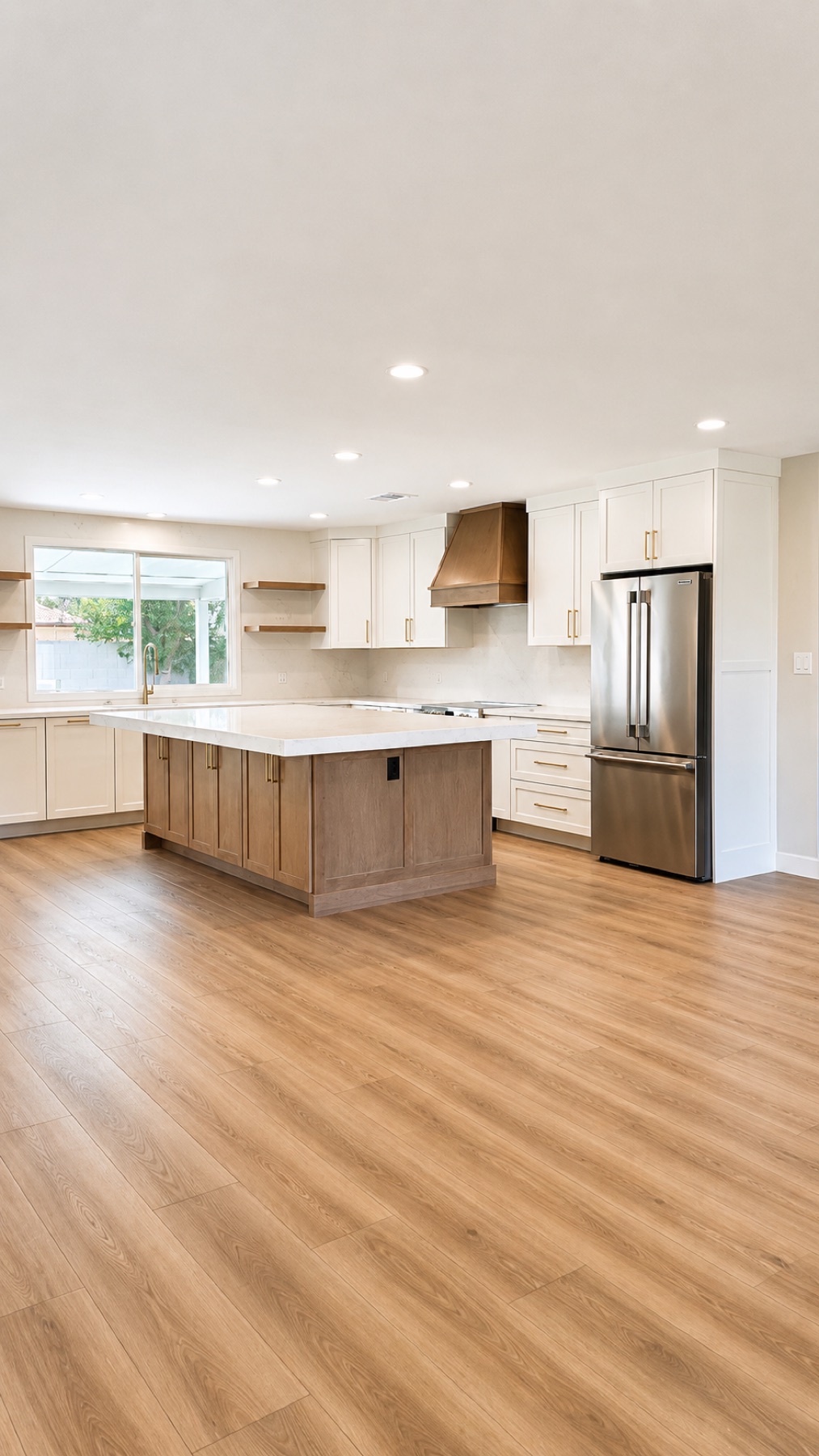 Remodeled kitchen at the back of the home with white cabinetry, a large quartz-topped island, and a custom wood hood