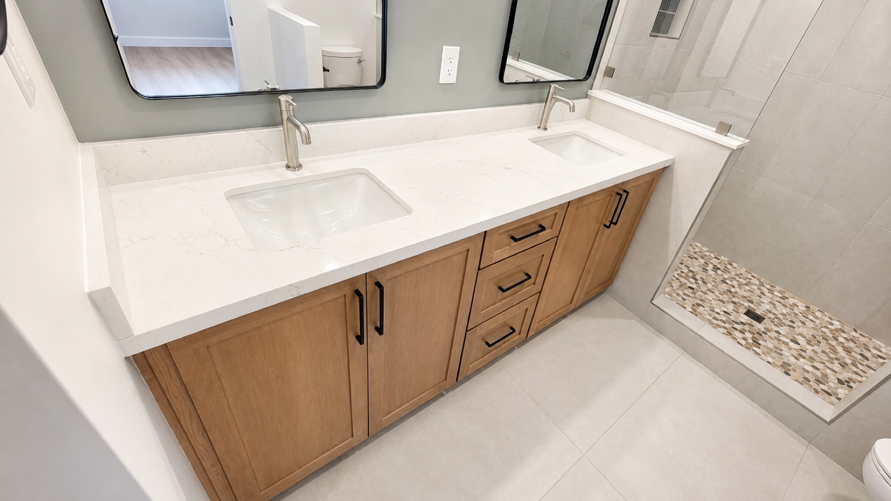New primary bathroom double vanity with a custom white oak cabinet, quartz counter, matte black fixtures, and two framed mirrors