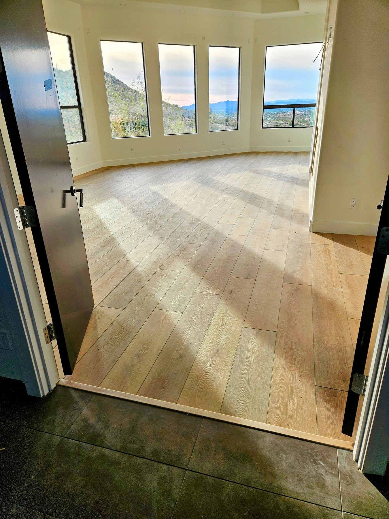 New wide-plank flooring in a sunlit room with mountain views