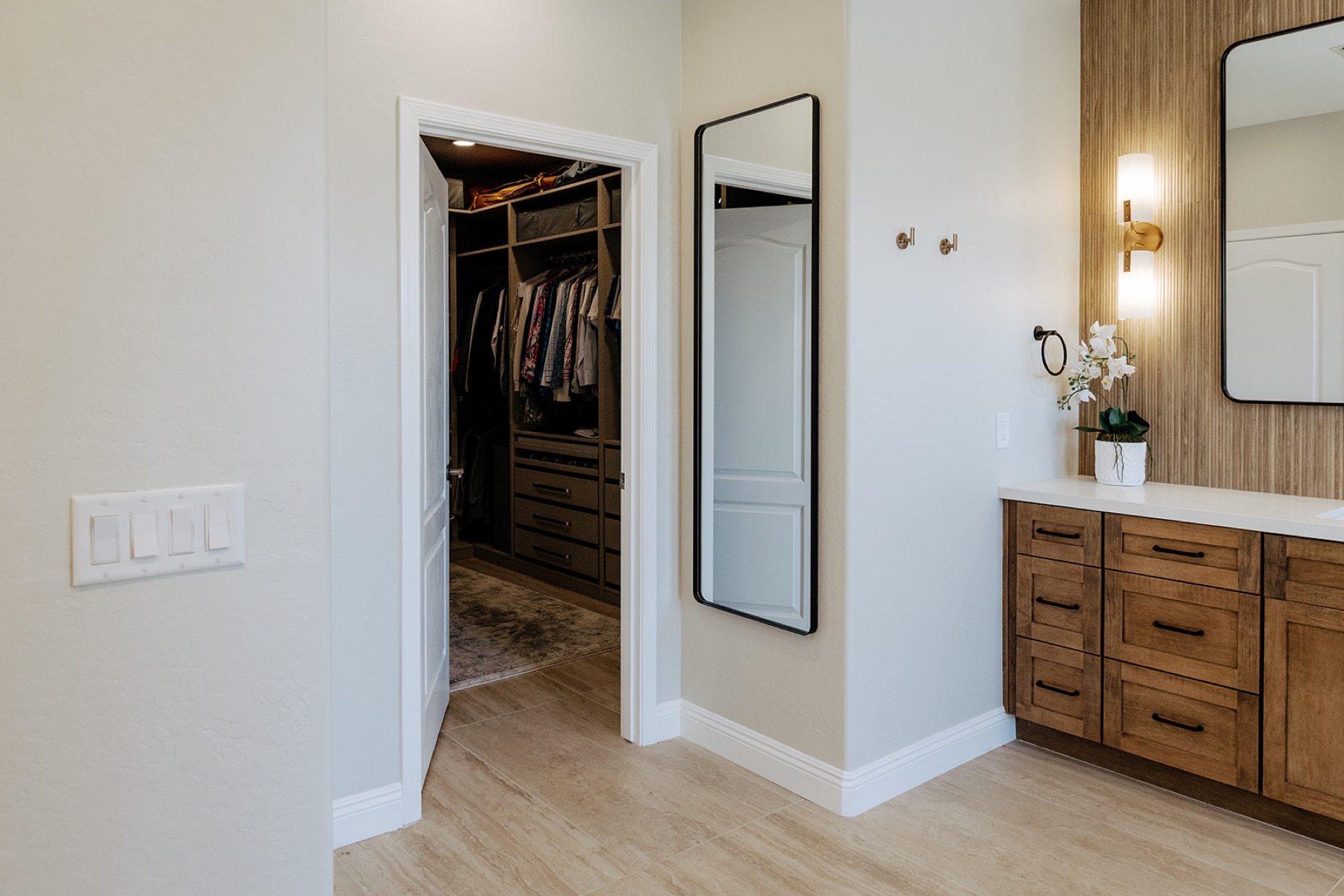 Full-length black-framed mirror in the hallway leading to the primary bathroom's walk-in closet