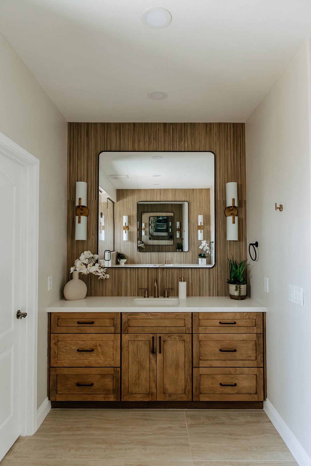 Second vanity nook down the hall with matching stained wood cabinetry, reeded tile, and brass fixtures
