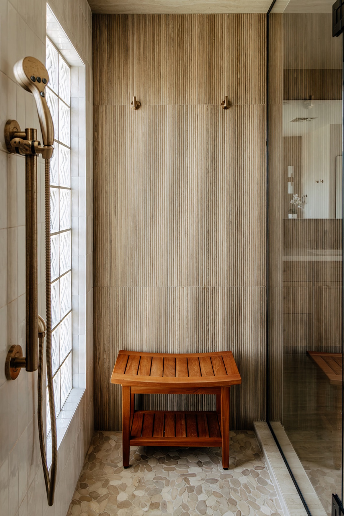 New walk-in shower with a reeded wood-look tile accent wall, a built-in teak bench, and the original glass block window