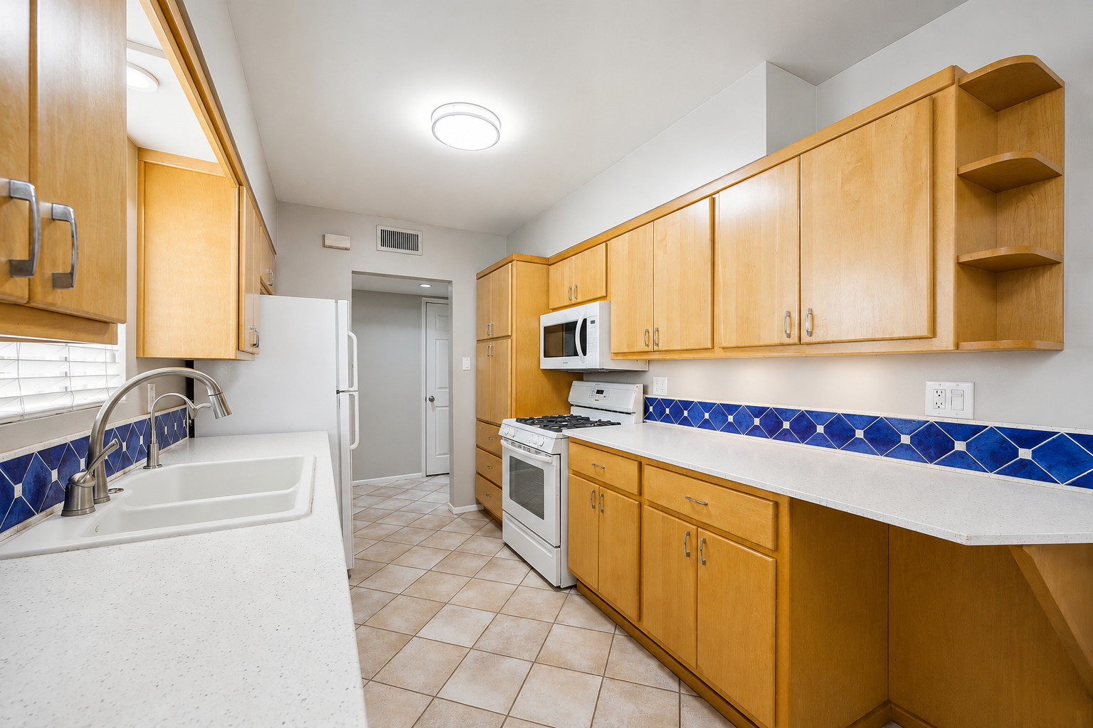 Original closed-off galley kitchen with honey oak cabinets and blue tile backsplash before the remodel